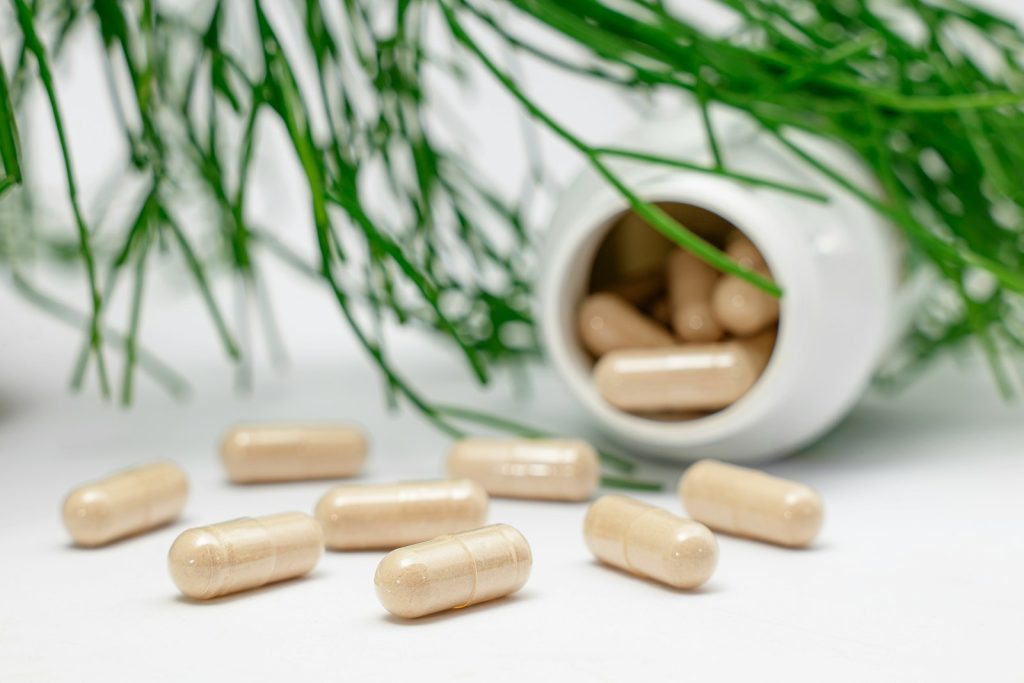 Gélules de probiotiques renversées d'un flacon blanc, illustrant un complément probiotique envisagé pour l'eczéma