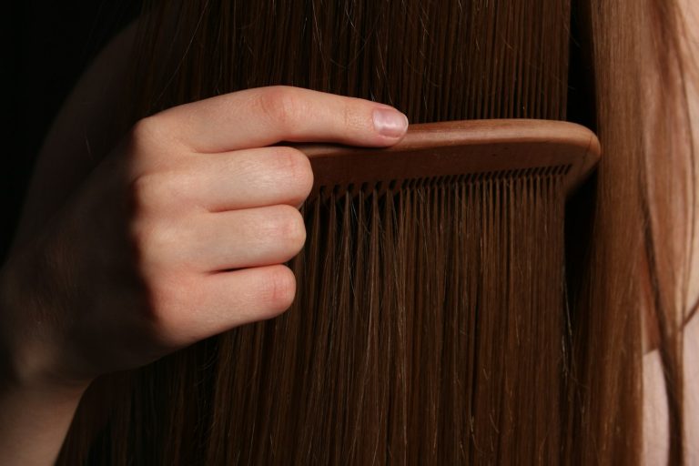 Une main coiffe une longue chevelure brune, illustrant la pousse et l'entretien du cheveu
